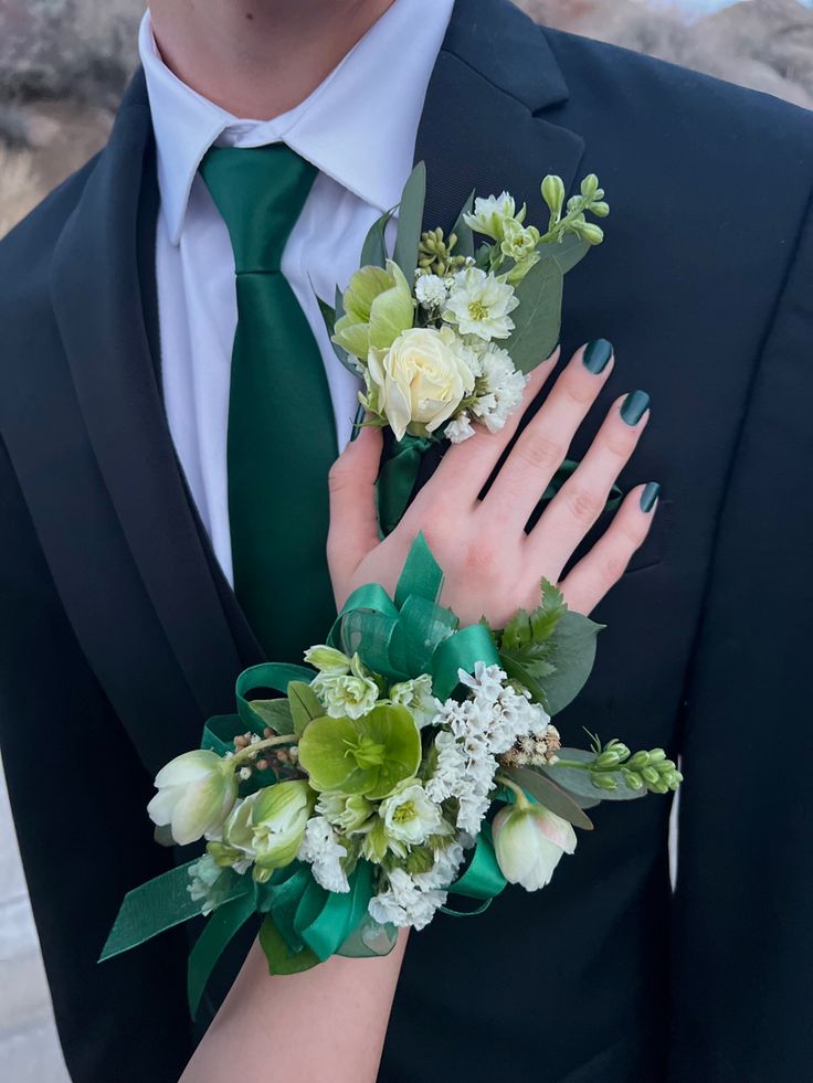 a close up of a person wearing a suit and tie with flowers on his arm