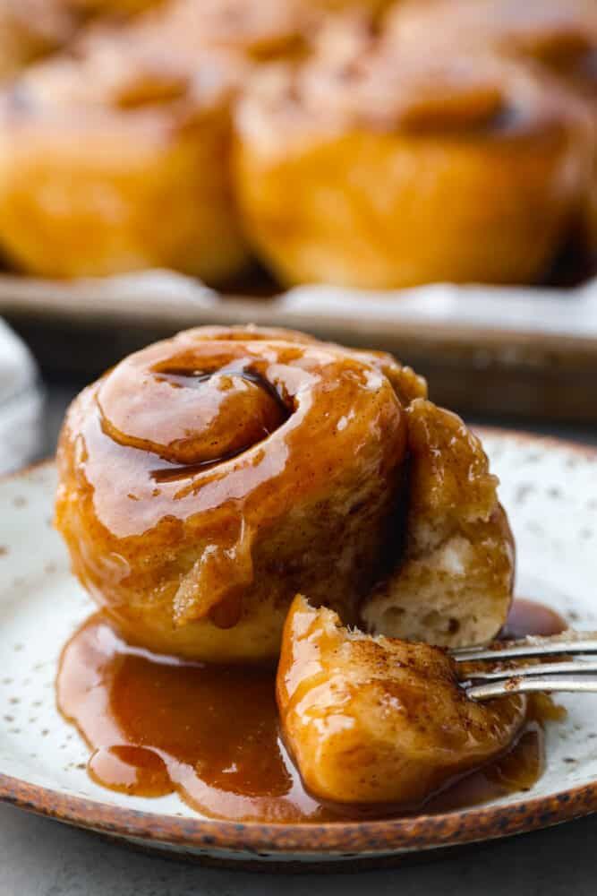 two cinnamon rolls on a plate with caramel sauce drizzled over them