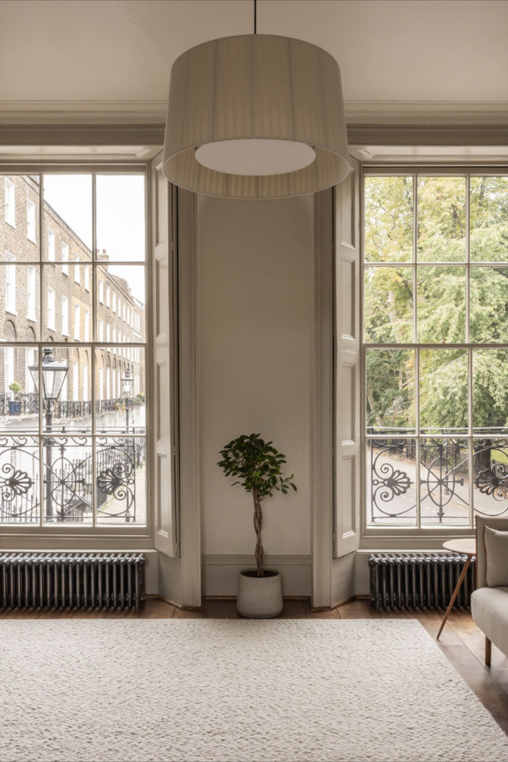 a living room with large windows and a rug on the floor in front of it