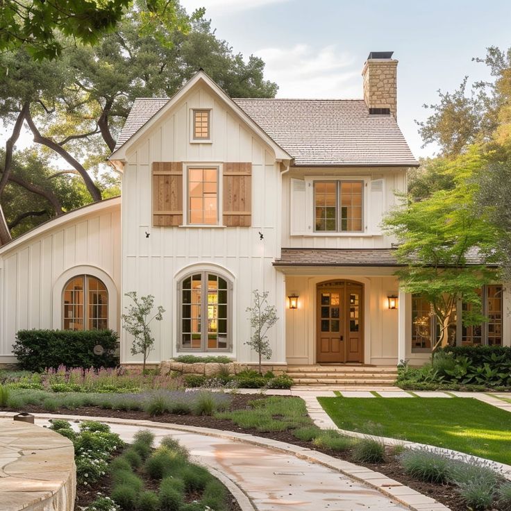 a large white house with lots of windows and plants in the front yard, surrounded by greenery