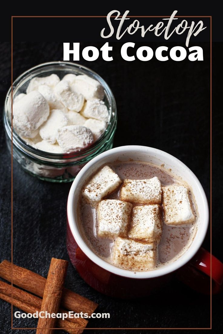 hot chocolate with marshmallows in a red mug and cinnamon sticks next to it