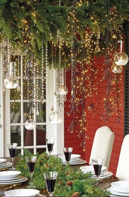 a dining room table with christmas decorations and lights hanging from it's ceiling over it