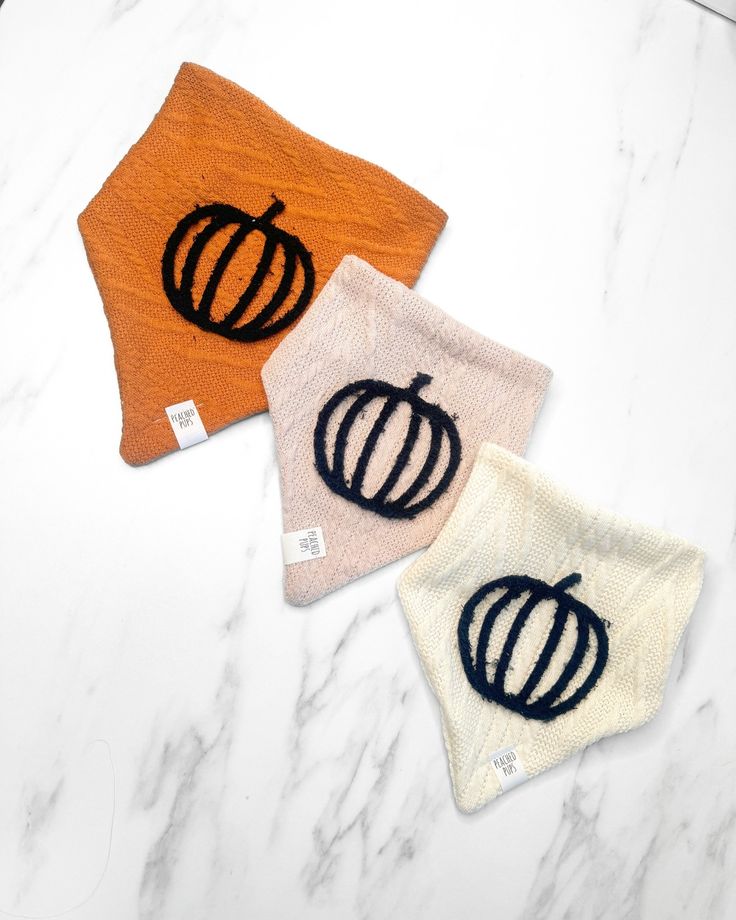 three orange and white dish towels with black designs on them sitting on a marble surface