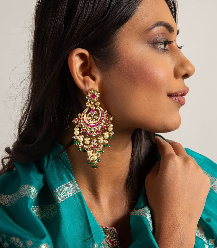 Step into refined elegance with the Nishi red & green kundan chandbali, a captivating blend of vibrant colors and exquisite craftsmanship. These chandbalis feature radiant red and green kundan stones, beautifully set in intricate gold detailing that enhances their allure. Perfect for festive occasions, they add a touch of regal charm to your look, ensuring you stand out with every elegant sway. Temple Jewelry Style Kundan Chandbalis With Meenakari, Kundan Meenakari Chandbalis For Festive Occasions, Fusion Kundan Bridal Earrings With Cutdana, Festive Kundan Chandbalis With Meenakari, Festive Kundan Chandbalis With Meenakari Details, Fusion Bridal Earrings With Kundan And Cutdana, Green Fusion Chandbalis For Celebrations, Fusion Style Kundan Jhumkas With Gota Work, Heavy Green Kundan Chandbalis