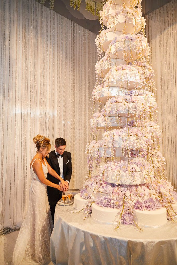 a bride and groom cutting their wedding cake together in front of a large multi - tiered cake