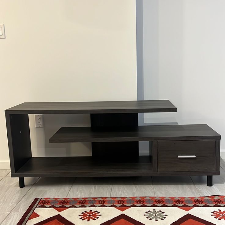 a black entertainment center sitting on top of a white floor next to a red rug