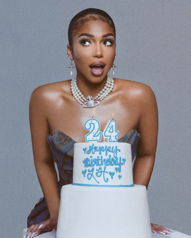 a woman holding a birthday cake with the number twenty four in front of her face