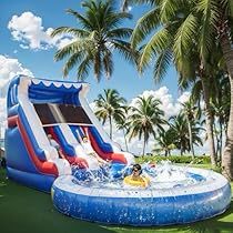 an inflatable water slide is on the lawn next to palm trees and blue skies