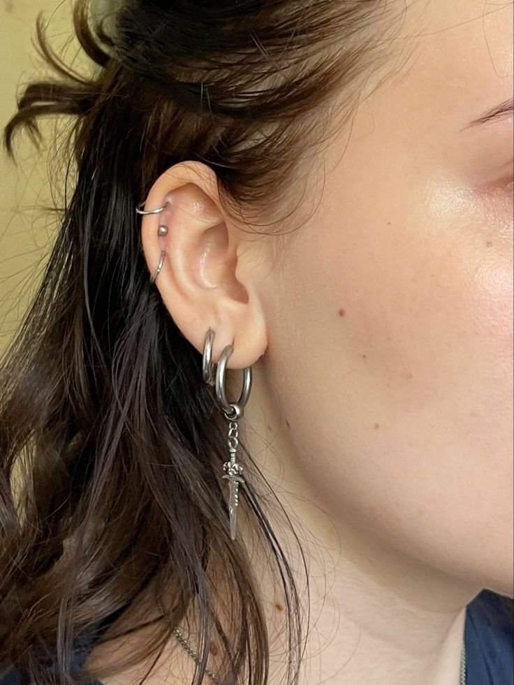 a close up of a person with ear piercings on their ears and wearing earrings