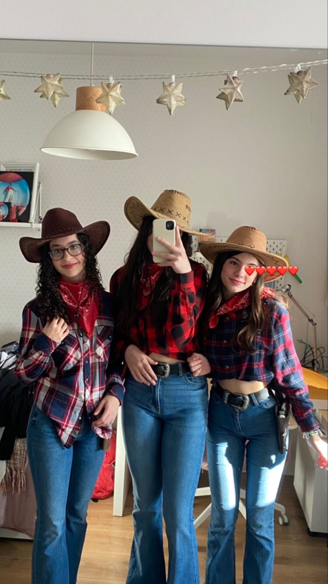 three women wearing cowboy hats and jeans posing for the camera