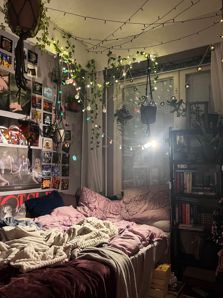 an unmade bed sitting under a window next to a book shelf filled with books