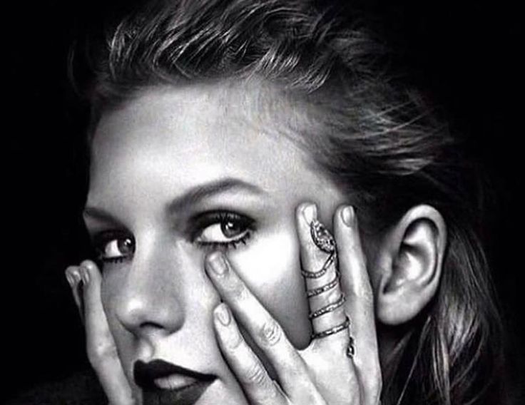 black and white photograph of a woman with her hands on her face, looking at the camera