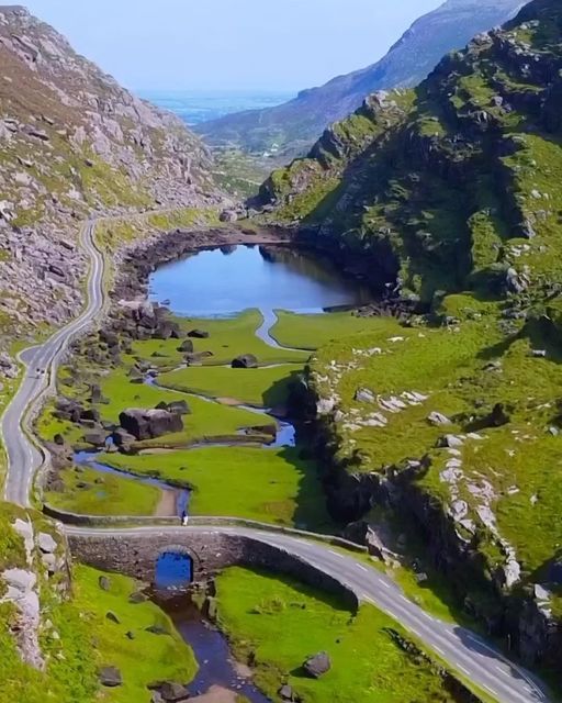 an aerial view of a winding road in the mountains with a river running through it