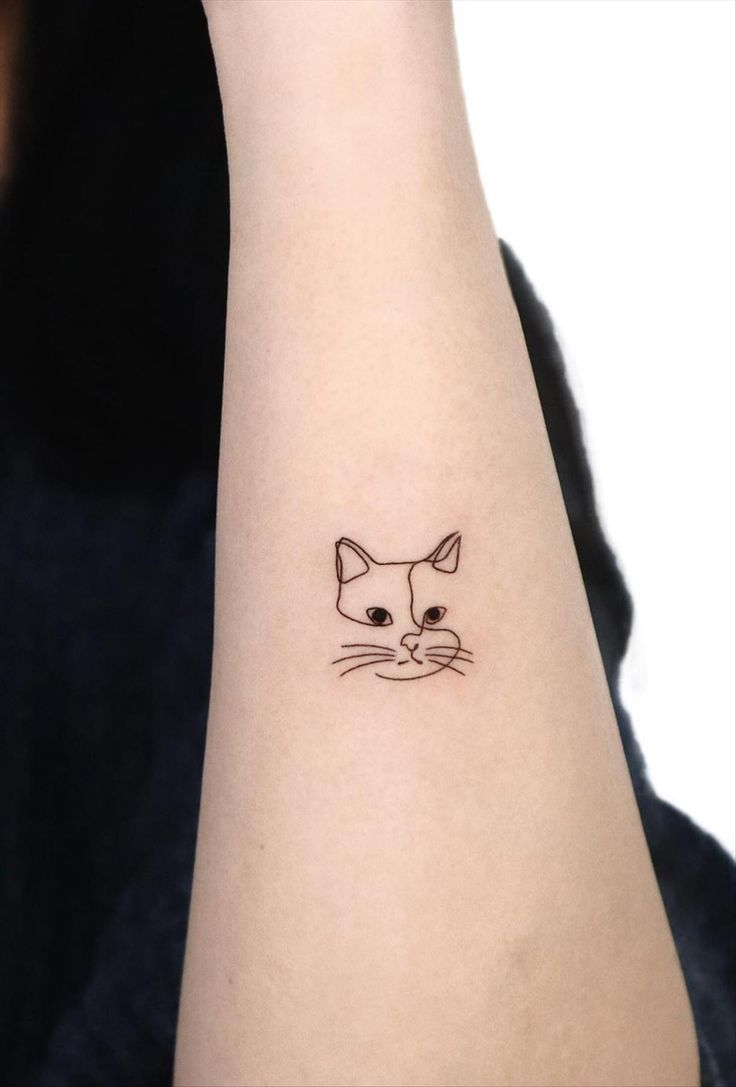 a small cat tattoo on the left wrist and right arm, with an outline of a cat's face