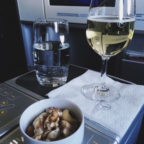 a bowl of food next to a glass of wine on an airplane