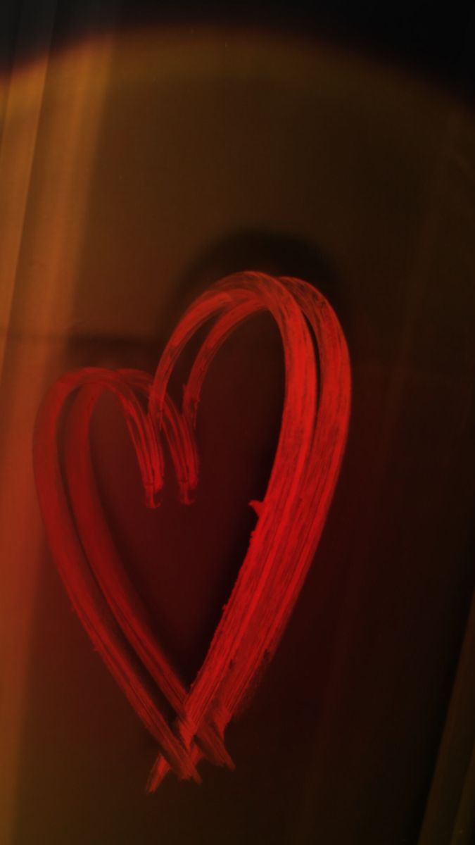 a red heart shaped object is shown in the middle of a blurry image with light coming from it