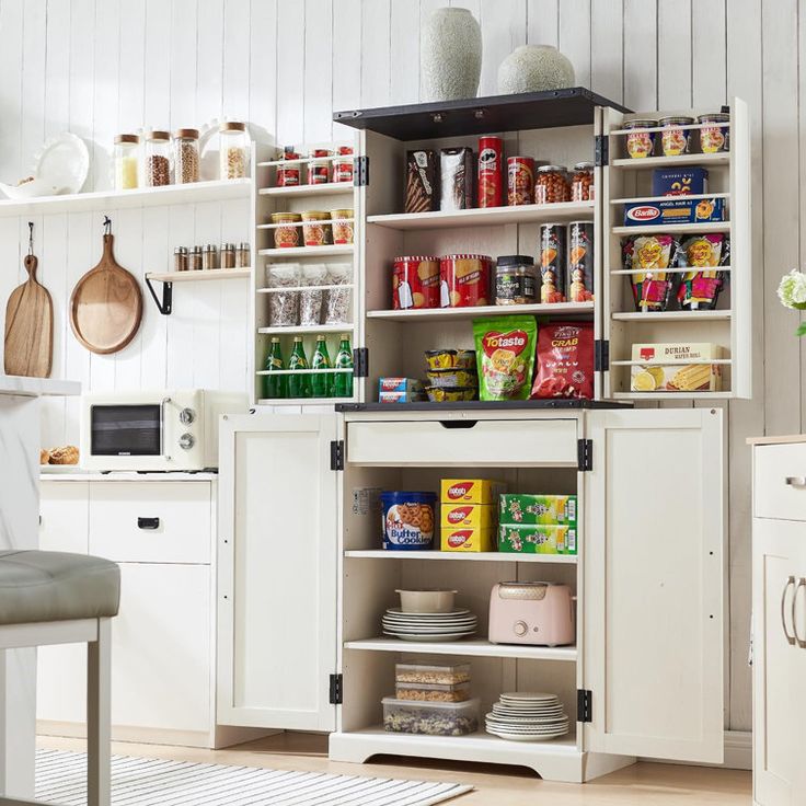 a kitchen with white cabinets and shelves filled with food