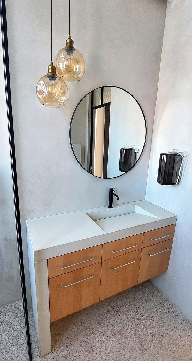 a bathroom with two sinks and a round mirror on the wall above it is also a light fixture