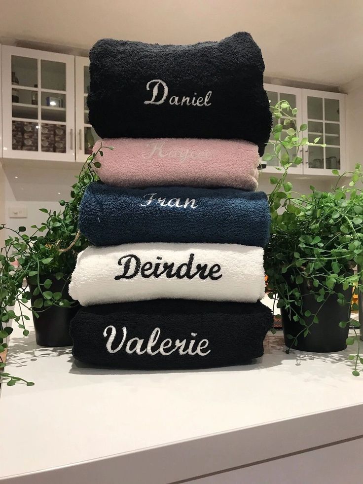 towels stacked on top of each other in front of potted plants and kitchen cabinets