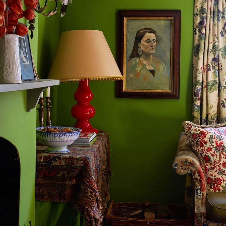 a living room with green walls and floral curtains on the window sill next to a couch