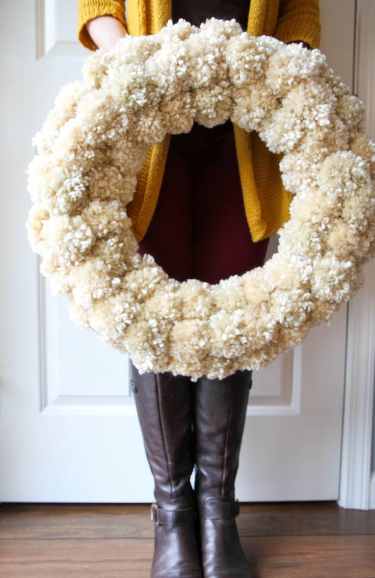 a woman standing in front of a door with a wreath on her knee and boots