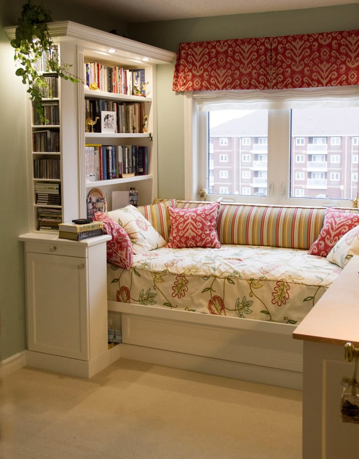 a living room filled with furniture next to a window covered in red and white curtains