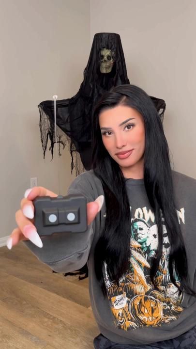 a woman sitting on the floor with a remote control in her hand and a ghost behind her