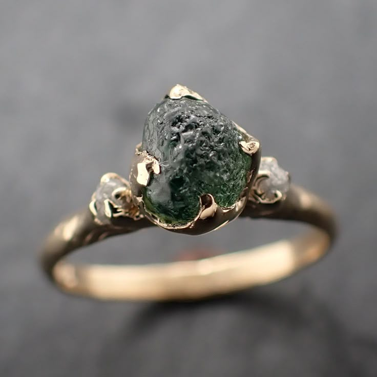 Raw rough green Montana sapphire surrounded by two raw conflict-free diamonds. I hand carved this ring in wax and cast it in solid 14k yellow gold using the lost wax casting process. This one of a kind raw gemstone ring is a size 7 it can be resized up or down. The sapphire stone measures about 6.5 x 5.5mm. The rough diamonds are about 2mm. The band is around 2mm. Throughout all time and history in every tribe and culture all around the world crystals, minerals and gemstones have used for healin Raw Stone Wedding Ring, Raw Moss Agate Ring, Raw Sapphire Jewelry, Uncut Gem Ring, Raw Engagement Rings, Raw Emerald Engagement Ring, Wedding Ring Gemstone, Green Saphire Ring, Raw Gemstone Engagement Rings