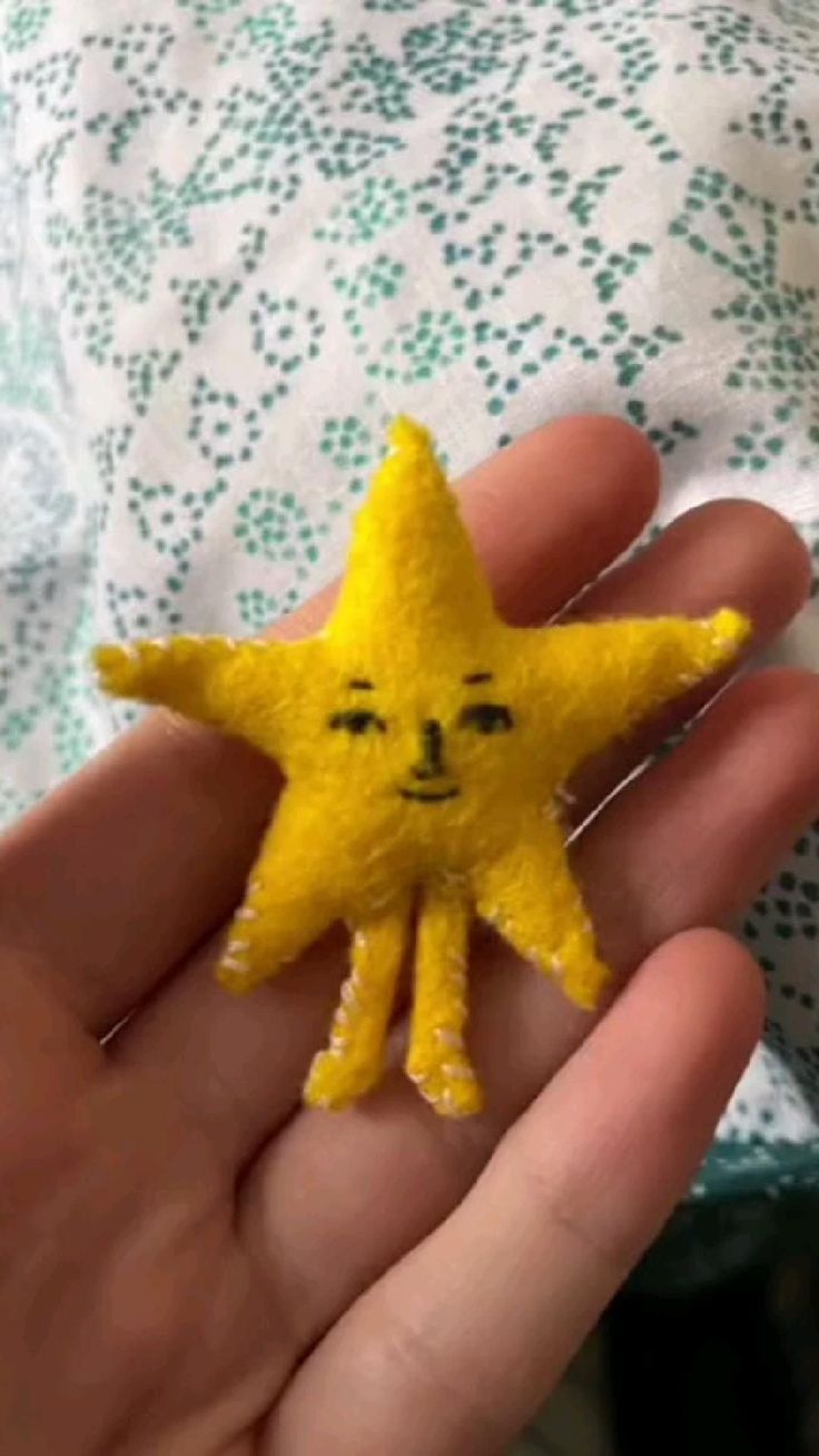 a hand holding a small yellow star with a face drawn on it's side