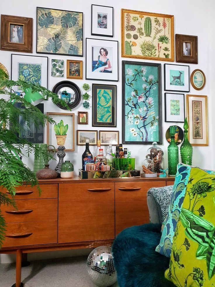 a room filled with lots of pictures on the wall and green furniture in front of it