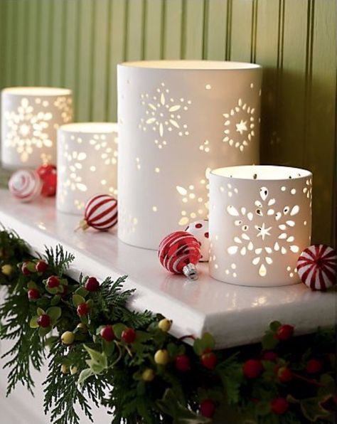 three white candles sitting on top of a mantle next to christmas wreaths and candy canes