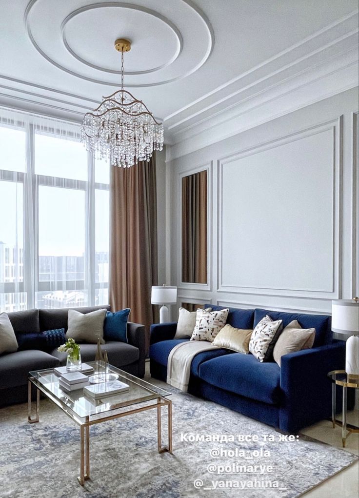 a living room filled with furniture and a chandelier hanging above the couches