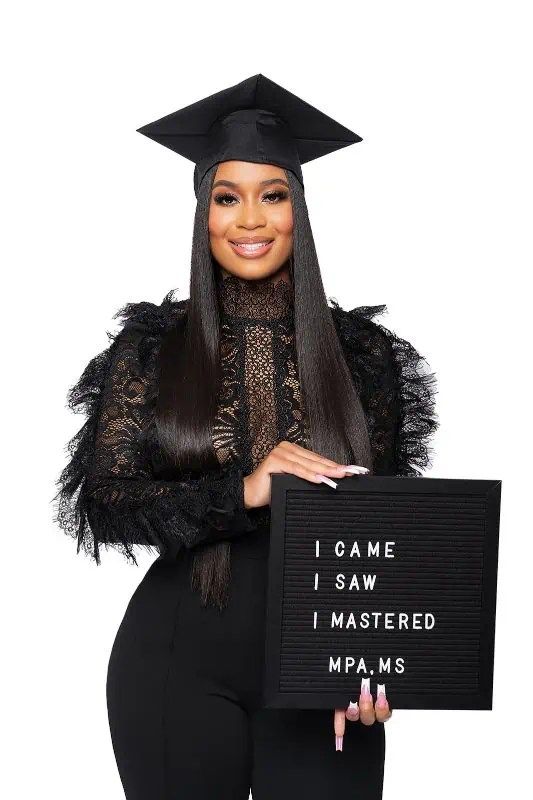 a woman wearing a graduation cap and gown holding a sign