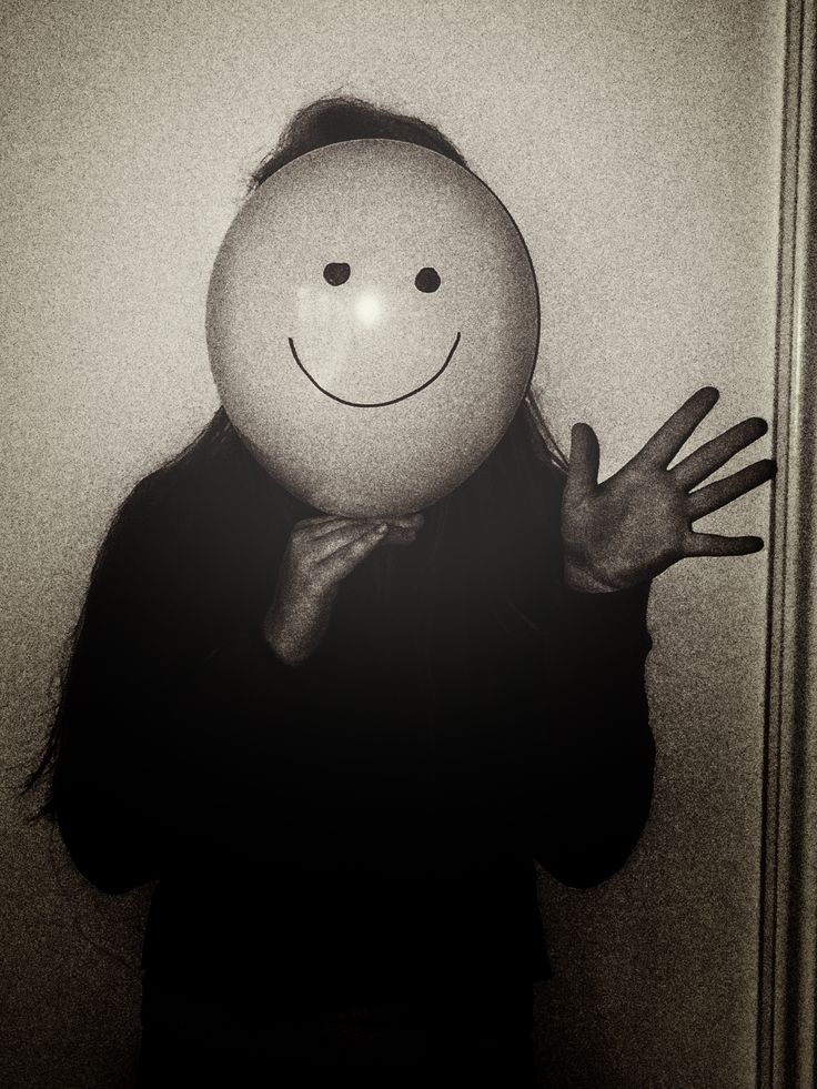 a person with a smiley face holding up a balloon