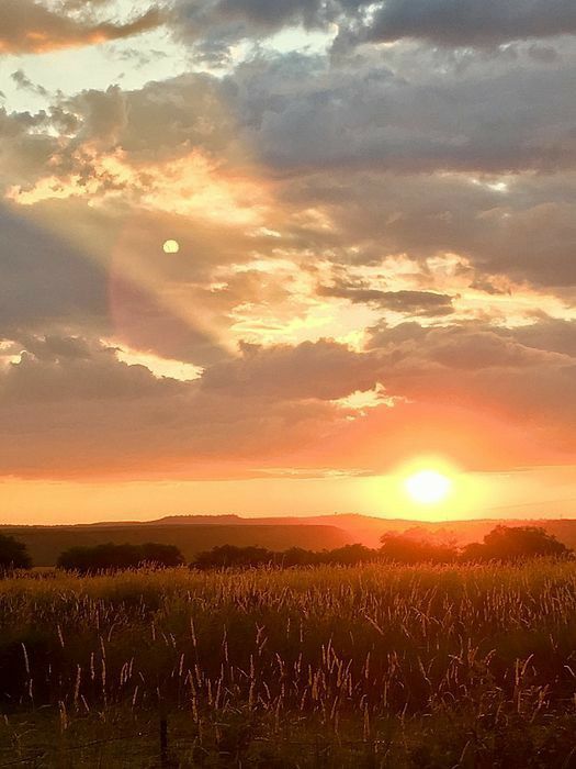 the sun is setting over an open field