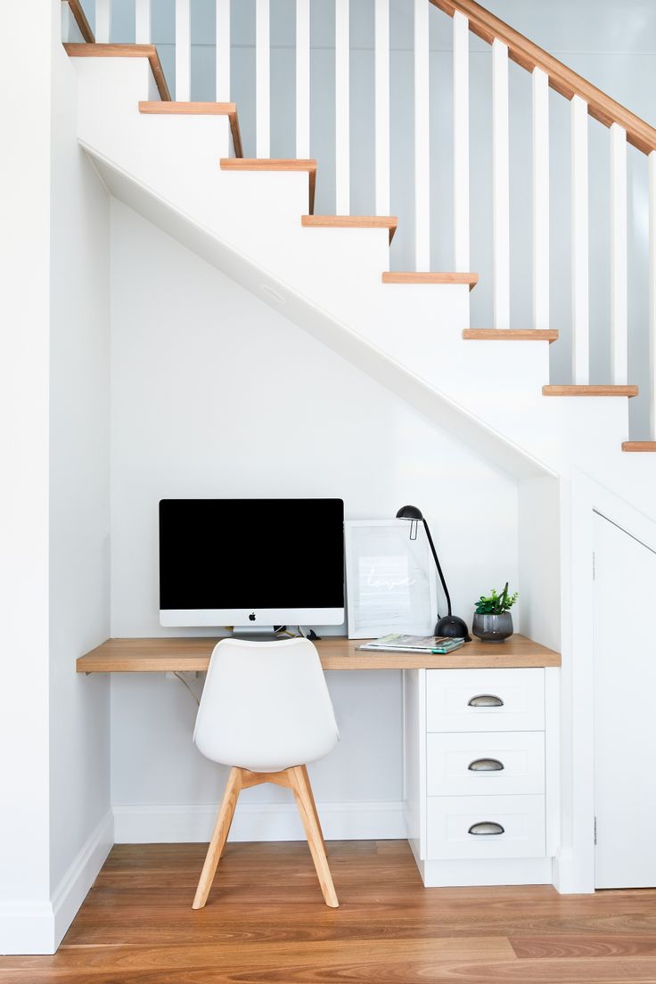 a desk with a computer on it under the stairs