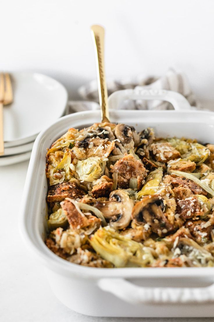 a casserole dish with mushrooms and other vegetables in it on a white table