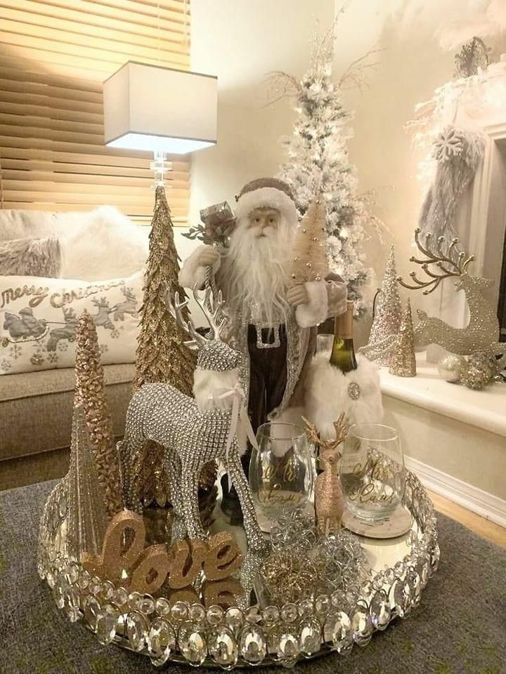 a santa clause sitting on top of a silver tray next to christmas trees and other decorations