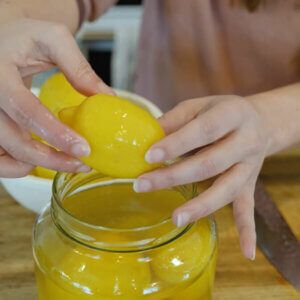 a woman is peeling an orange into a jar