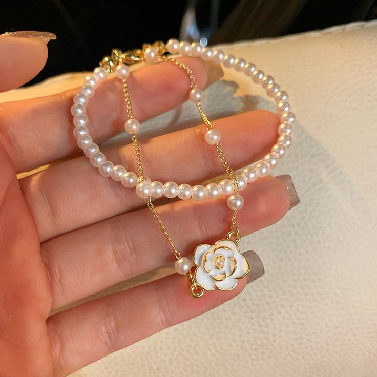 ✦ Embrace the delicate beauty of our Dainty Pearl Chain Camellia Pendant Bracelet. This charming bracelet features lustrous pearls elegantly arranged along a dainty chain, culminating in a stunning camellia flower pendant. The camellia symbolizes love, beauty, and devotion, making this bracelet a perfect expression of femininity and grace. Crafted with attention to detail, the combination of pearls and the camellia pendant creates a timeless and sophisticated piece of jewelry. Whether for a special occasion or everyday wear, our Dainty Pearl Chain Camellia Pendant Bracelet adds a touch of elegance to any ensemble. Embrace the enchantment of pearls and the symbolism of the camellia flower with this stunning bracelet. ----------- DETAILS ------------ - Size (Length): 21.7cm- Materials: Coppe Elegant Pearl Charm Bracelet, White Pearl Bracelets With Adjustable Chain, Delicate Pearl Bracelet For Party, White Pearl Chain Bracelets For Party, Feminine Pearl Bracelet For Gifting, White Pearl Bracelet With Chain, White Pearl Bracelet With Adjustable Chain, White Pearl Bracelet With Chain Detail, Feminine Pearl Bracelets As Gift