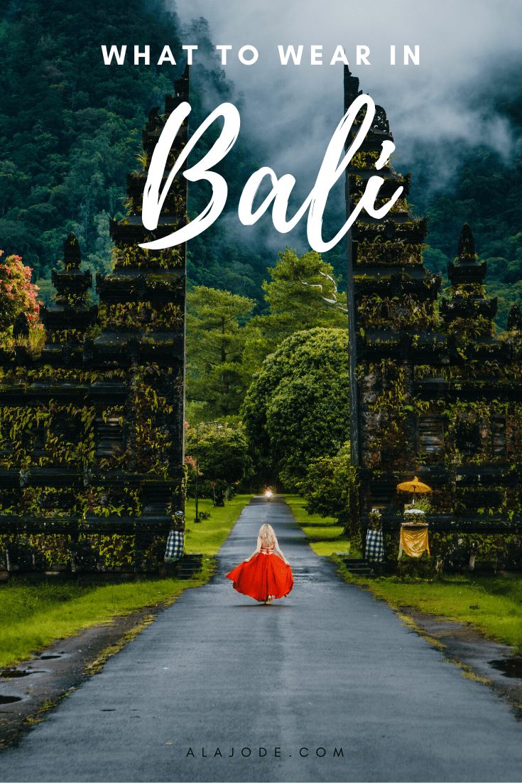 a woman in a red dress walking down a road with the words what to wear in bali