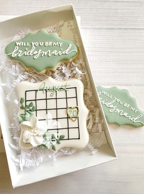 a cookie in a box that says will you be my bridesmaid?