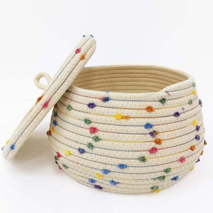 a white basket with multicolored beads and a wooden stick sticking out of it