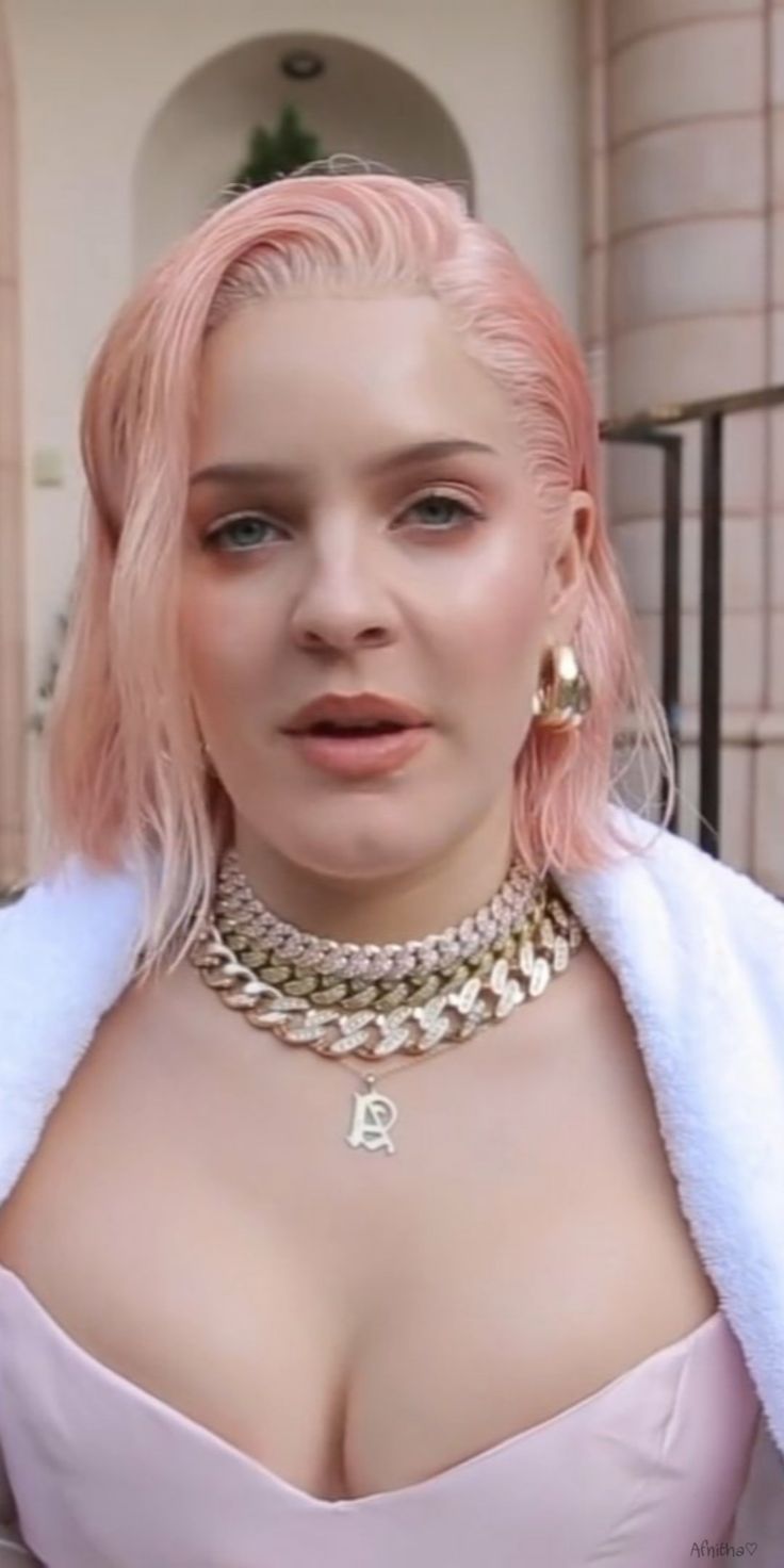 a woman with pink hair wearing gold jewelry