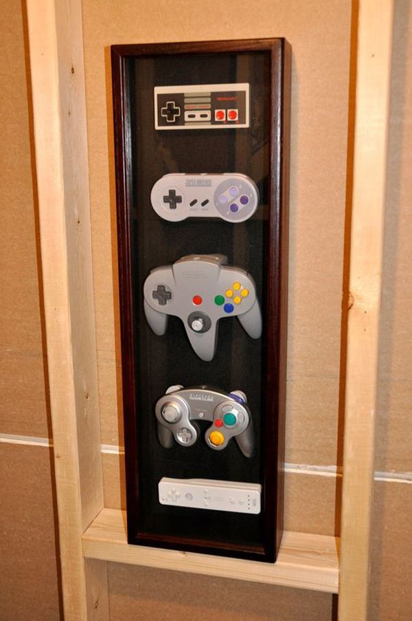 a display case with two video game controllers in front of it on the wall next to a toilet