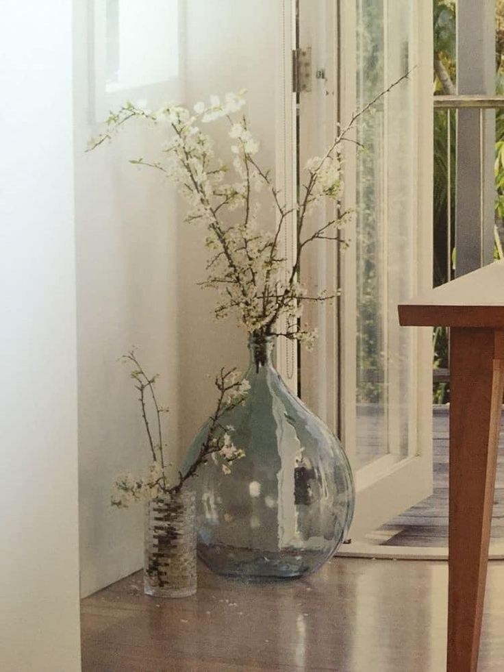 there is a vase with flowers in it sitting on the floor next to a table