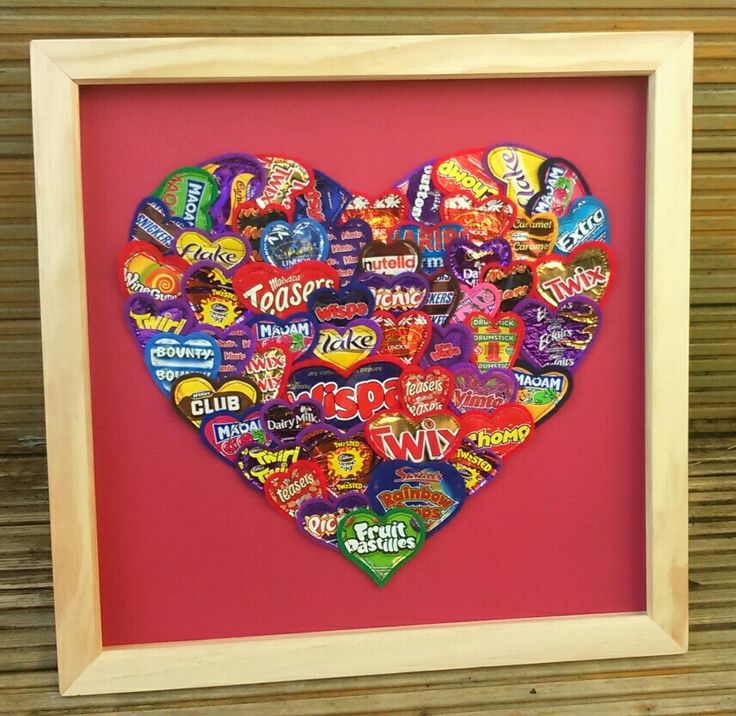 a wooden frame with a heart shaped cut out of candy candies on the inside