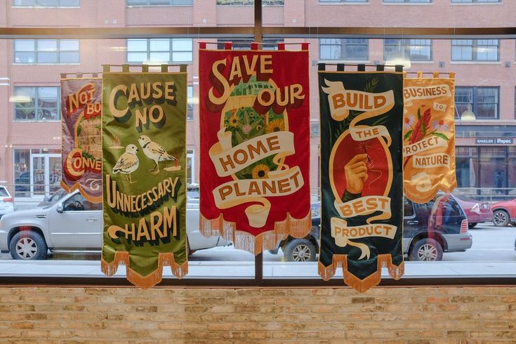 colorful banners hanging from the side of a building in front of a window with cars parked outside