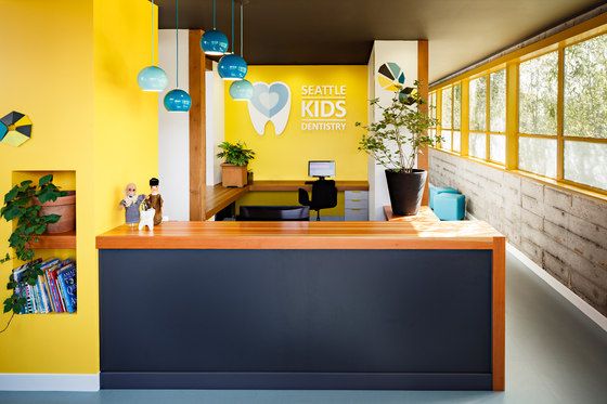 an office with yellow walls and blue counter tops, plants on the wall and bookshelves