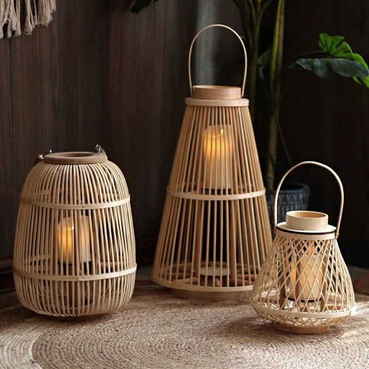 three bamboo lanterns with lights inside on a table next to a potted plant and rug